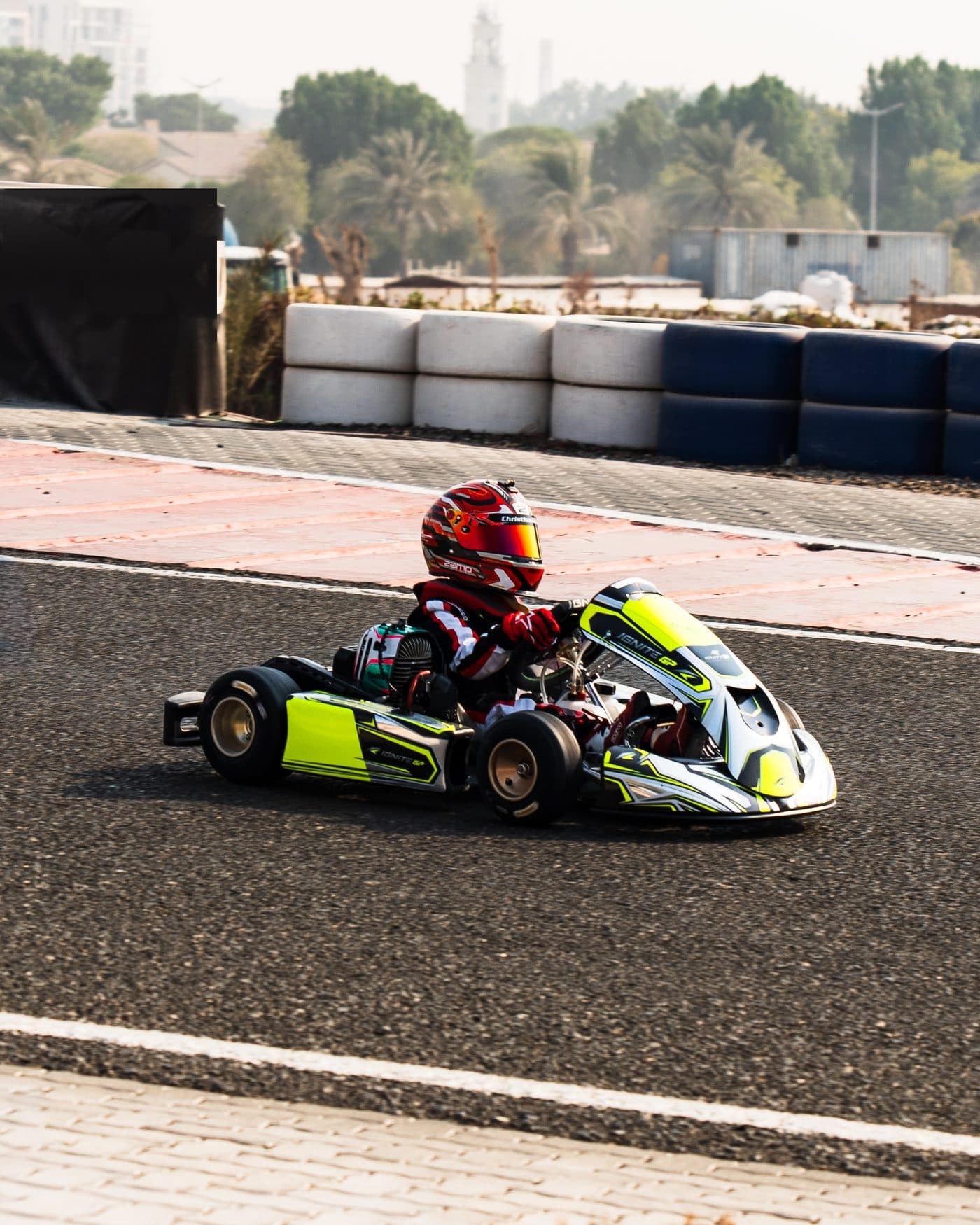 Bambino driver on track with the Dubai skyline and palms behind the circuit